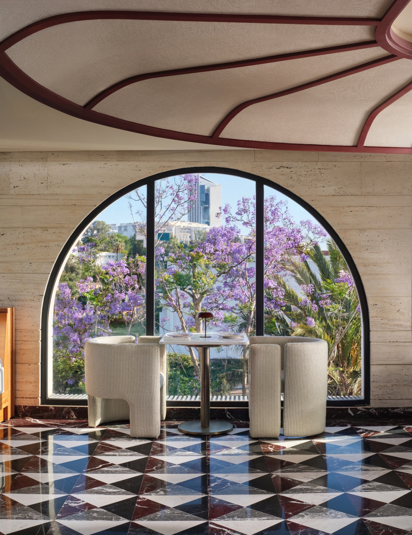 Beyti arched window framing a jacaranda tree in bloom over the harlequin marble floor