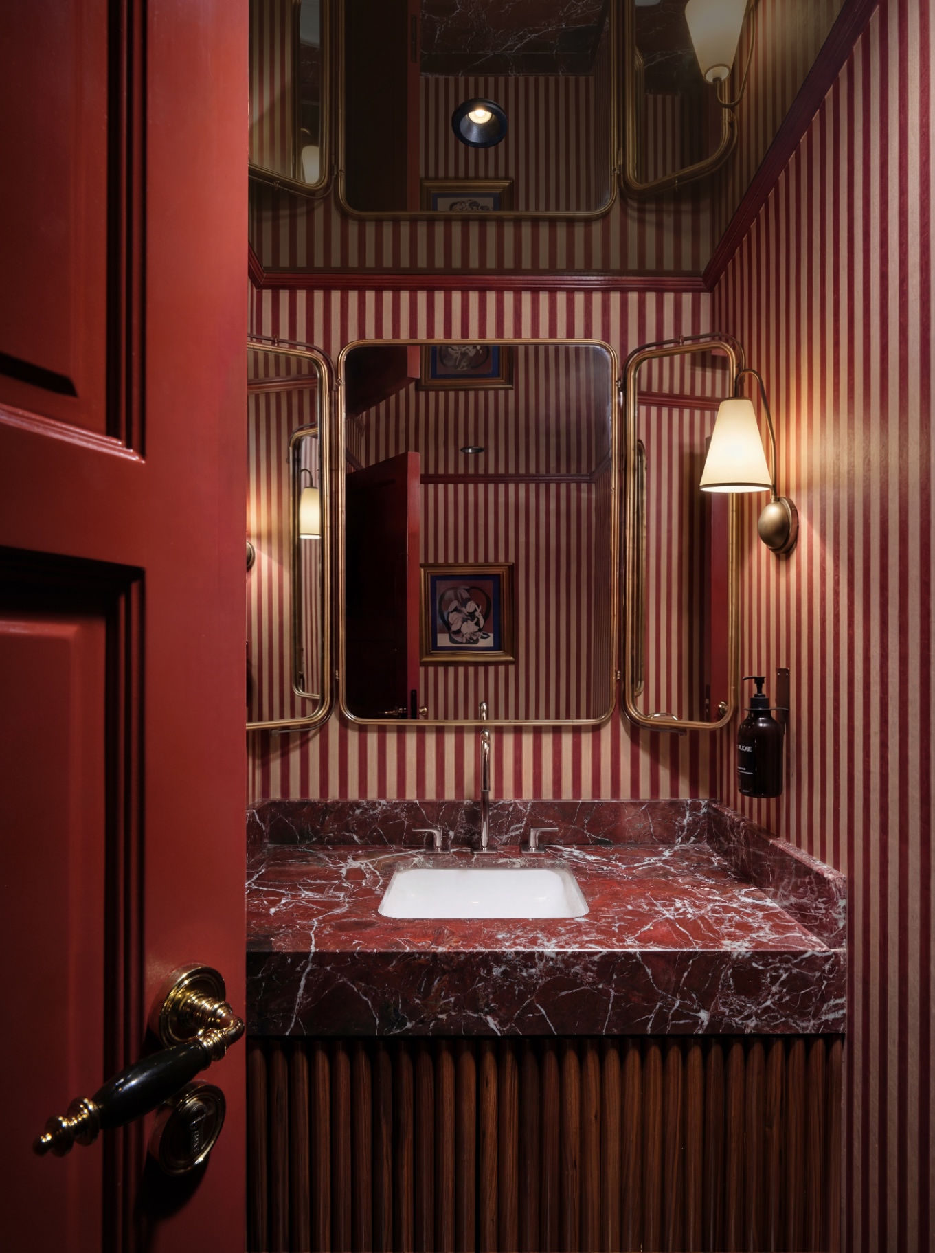 Beyti striped crimson powder room with rosso marble vanity and brass fittings